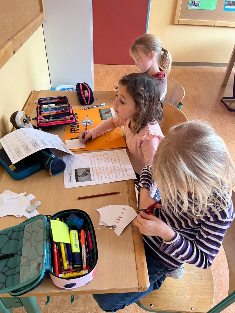 Eine Gruppe von Kindern, die an einem Tisch sitzen und auf Papier schreiben